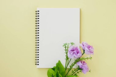 Spiral Not Defteri ya da Pastel Yellow Minimalist Arkaplan 'da Çizgisiz Tür ve Mor Çiçek Defteri. Spiral Not Defteri Orta Çerçeve 'ye uydur