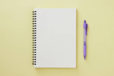 Spiral Notebook veya Spring Notebook in Unline Type and Purple Pen on Pastel Yellow Minimalist Arkaplan. Spiral Not Defteri Orta Çerçeve 'ye uydur