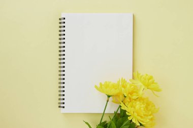 Spiral Notebook veya Spring Notebook in Unline Type and Yellow Flower on Pastel Yellow Minimalist Arkaplan. Spiral Not Defteri Orta Çerçeve 'ye uydur