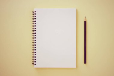 Spiral Notebook veya Spring Notebook in Unline Type and kalem on Pastel Yellow Minimalist Arkaplan. Spiral Not Defteri Orta Çerçeve 'ye Eski Ton' da Uygula