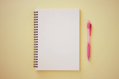 Spiral Notebook veya Spring Notebook in Unline Type and Pink Pen on Pastel Yellow Minimalist Arkaplan. Spiral Not Defteri Orta Çerçeve 'ye Eski Ton' da Uygula