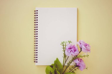 Spiral Not Defteri ya da Pastel Yellow Minimalist Arkaplan 'da Çizgisiz Tür ve Mor Çiçek Defteri. Spiral Not Defteri Orta Çerçeve 'ye Eski Ton' da Uygula