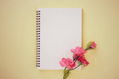 Spiral Notebook veya Spring Notebook in Unline Type and Rose Flower on Pastel Yellow Minimalist Arka plan. Spiral Not Defteri Orta Çerçeve 'ye Eski Ton' da Uygula