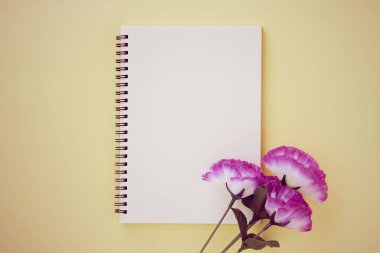 Spiral Notebook ya da Spring Notebook in Unline Type ve Violet Flower on Pastel Yellow Minimalist Arka plan. Spiral Not Defteri Orta Çerçeve 'ye Eski Ton' da Uygula