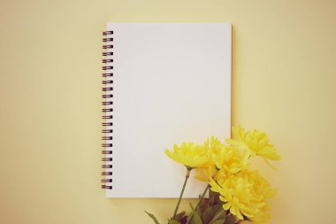 Spiral Notebook veya Spring Notebook in Unline Type and Yellow Flower on Pastel Yellow Minimalist Arkaplan. Spiral Not Defteri Orta Çerçeve 'ye Eski Ton' da Uygula