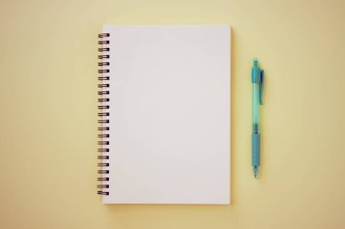 Spiral Notebook veya Spring Notebook in Unline Type and Green Pen on Pastel Yellow Minimalist Arkaplan. Spiral Not Defteri Orta Çerçeve 'ye Eski Ton' da Uygula