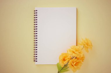 Spiral Not Defteri ya da Pastel Sarı Minimalist Arkaplan 'da Çizgisiz Tür ve Turuncu Çiçek ile Bahar Defteri. Spiral Not Defteri Orta Çerçeve 'ye Eski Ton' da Uygula