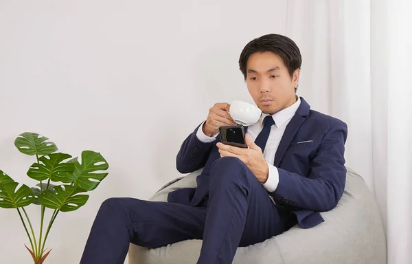 Asian Financial Advisor Drink Coffee See Smartphone Bean Bag Home — Φωτογραφία Αρχείου