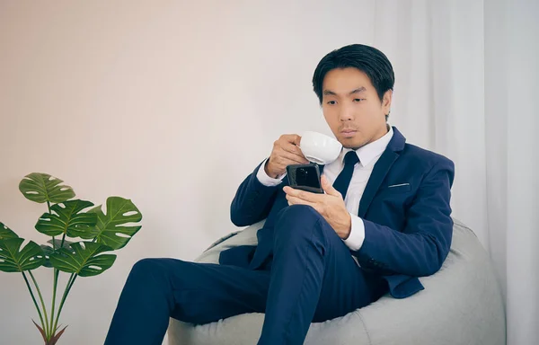 Asiatisk Finansiell Rådgivare Drick Kaffe Smartphone Bean Bag Home Office — Stockfoto