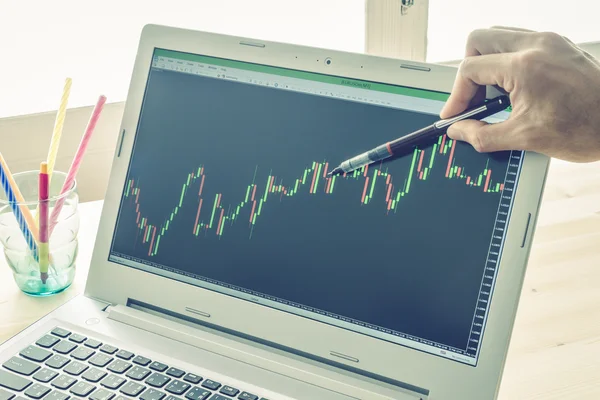 İşadamı noktası ve Forex grafik veya hisse senedi grafik mavi Vintage tarzı üzerinde sağ elinde kullanım kalem tarafından analiz