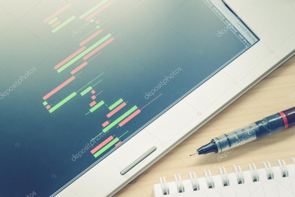 Stock or Forex Graph or Candlestick Chart in Tablet Screen and Pen and Notebook