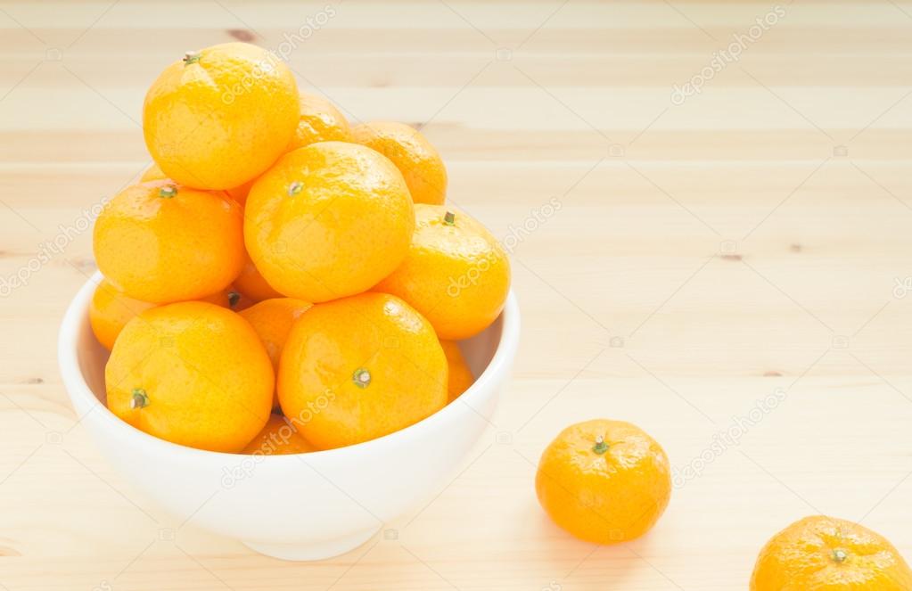 Mandarin or China Orange in White Bowl with two orange on wood table