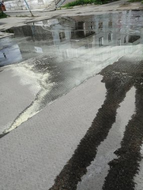 Asitli sülfür yağmurundan sonra su birikintisinin yüzeyinde görülebilir kükürt çizgileri var.