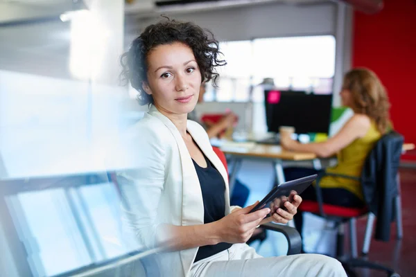 Conceptrice confiante travaillant sur une tablette numérique dans un espace de bureau créatif rouge — Photo