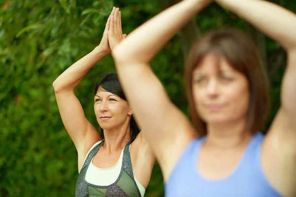 Dos mujeres maduras manteniéndose en forma haciendo yoga en el verano — Foto de Stock