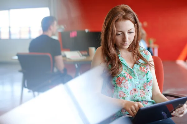 Αυτοπεποίθηση γυναικεία σχεδιαστή που εργάζεται σε μια ψηφιακή δισκίο σε κόκκινο δημιουργικών γραφείων — Φωτογραφία Αρχείου