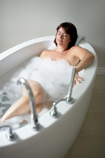 Serene mature woman with her eyes closed in a bathtub — Stock Photo, Image