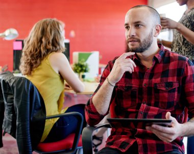 Dijital tablet kırmızı yaratıcı ofis alanı içinde çalışan kendine güvenen erkek tasarımcı