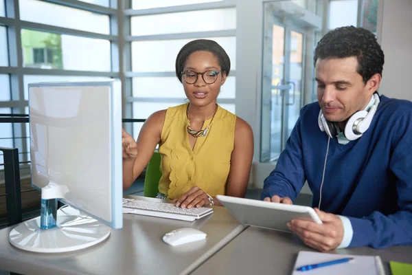 Dois colegas discutindo ideias usando um tablet e um computador — Fotografia de Stock