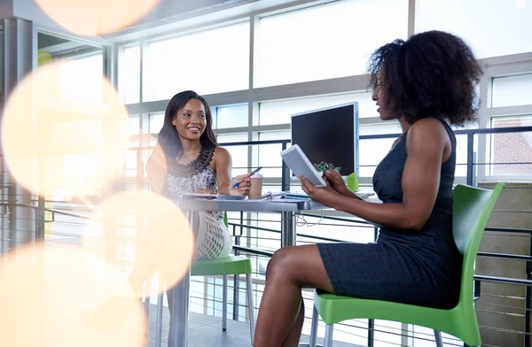 Twee Afro-Amerikaanse vrouwen bespreken van ideeën met behulp van een tablet en computer — Stockfoto