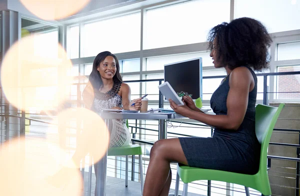 Dos mujeres afroamericanas discutiendo ideas usando una tableta y una computadora — Foto de Stock