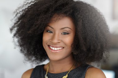 Portrait of a smiling business woman with an afro in bright glass office