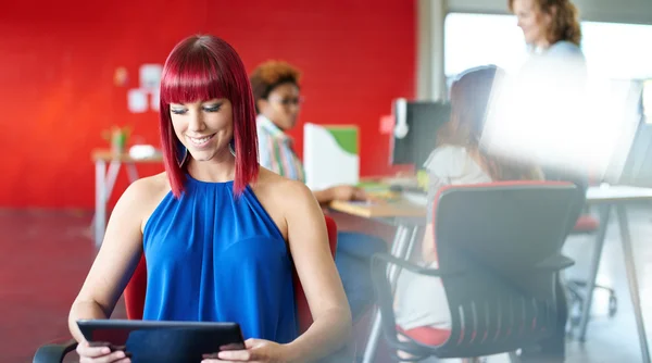 Designer feminina confiante trabalhando em um tablet digital no espaço de escritório criativo vermelho — Fotografia de Stock