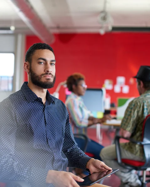 Diseñador masculino confiable trabajando en una tableta digital en el espacio de oficina creativo rojo —  Fotos de Stock