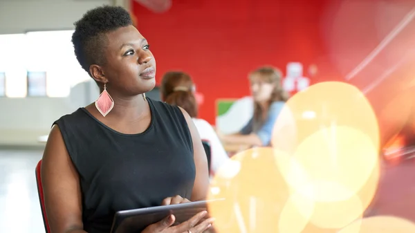 Confident female designer working on a digital tablet in red creative office space — Stock Photo, Image