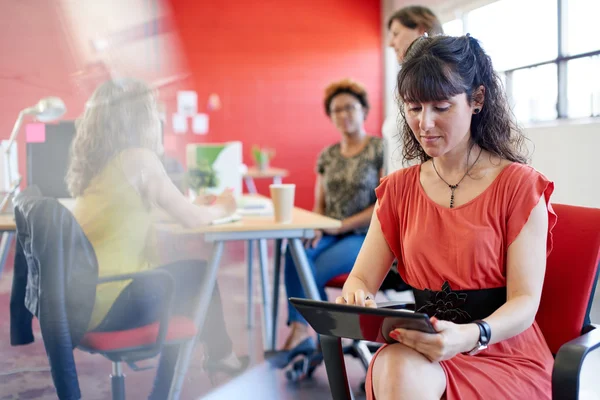 Designer feminina confiante trabalhando em um tablet digital no espaço de escritório criativo vermelho — Fotografia de Stock