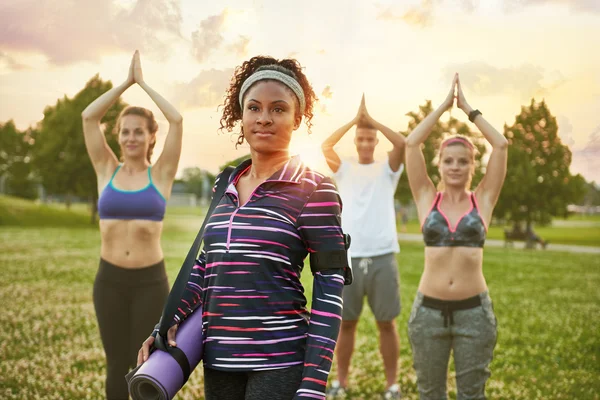 Young african-american woman leading a yoga class at sunset in nature park — Stock Photo, Image