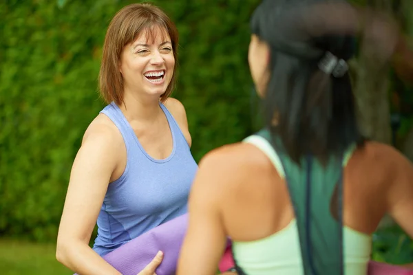 Twee rijpe vrouwen praten alvorens yoga te doen in de zomer — Stockfoto