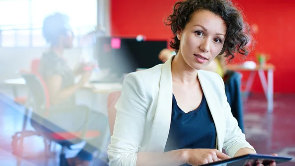 Conceptrice confiante travaillant sur une tablette numérique dans un espace de bureau créatif rouge — Photo