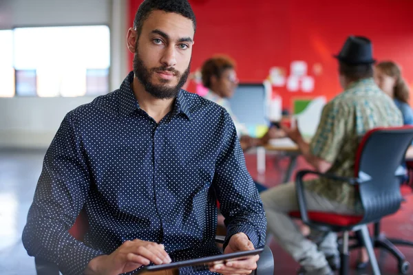 Designer masculino confiante trabalhando em um tablet digital no espaço de escritório criativo vermelho — Fotografia de Stock