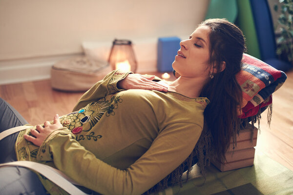 Привлекательная женщина смешанной расы, занимающаяся восстановительной йогой
