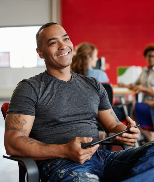 Diseñador masculino confiable trabajando en una tableta digital en el espacio de oficina creativo rojo —  Fotos de Stock