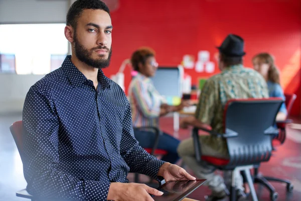 Designer masculino confiante trabalhando em um tablet digital no espaço de escritório criativo vermelho — Fotografia de Stock