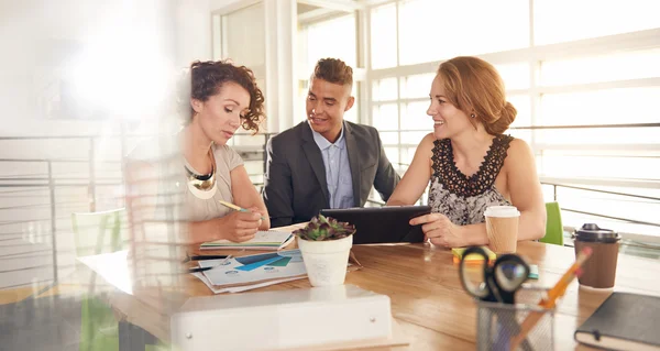 Bild von drei erfolgreichen Geschäftsleuten, die während einer Besprechung ein Tablet benutzen — Stockfoto