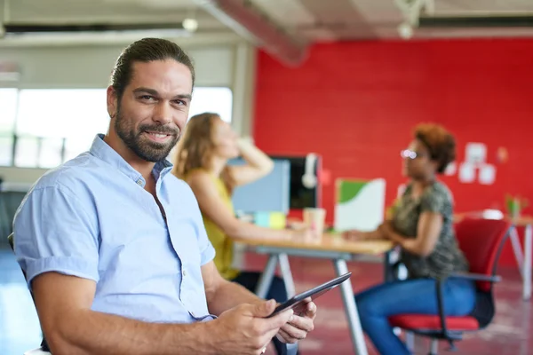 Diseñador masculino confiable trabajando en una tableta digital en el espacio de oficina creativo rojo —  Fotos de Stock