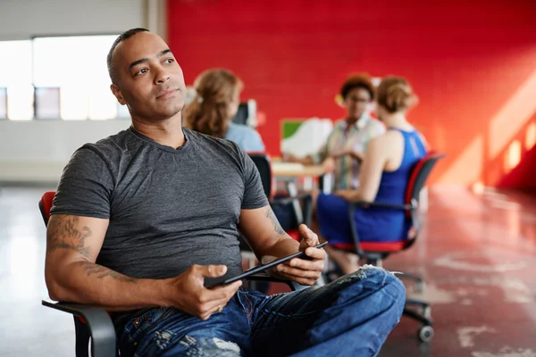 Diseñador masculino confiable trabajando en una tableta digital en el espacio de oficina creativo rojo — Foto de Stock