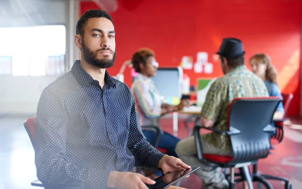 Diseñador masculino confiable trabajando en una tableta digital en el espacio de oficina creativo rojo — Foto de Stock