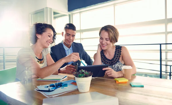 Imagem de três empresários bem sucedidos usando um tablet durante a reunião — Fotografia de Stock