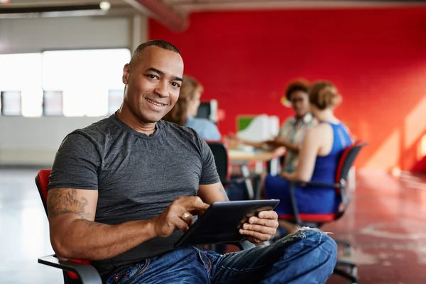 Designer masculino confiante trabalhando em um tablet digital no espaço de escritório criativo vermelho — Fotografia de Stock