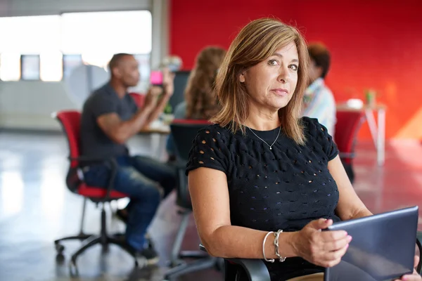 Уверенная женщина-дизайнер, работающая над цифровым планшетом в красном креативном офисе — стоковое фото