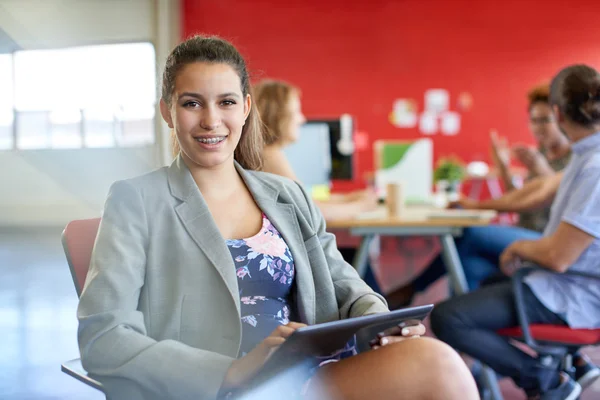 Diseñadora femenina segura trabajando en una tableta digital en un espacio de oficina rojo creativo — Foto de Stock