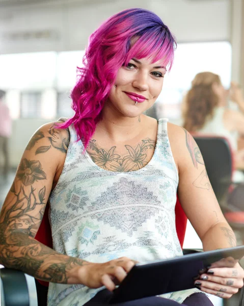 Confident and edgy female designer working on a digital tablet in red creative office space — Stock Photo, Image