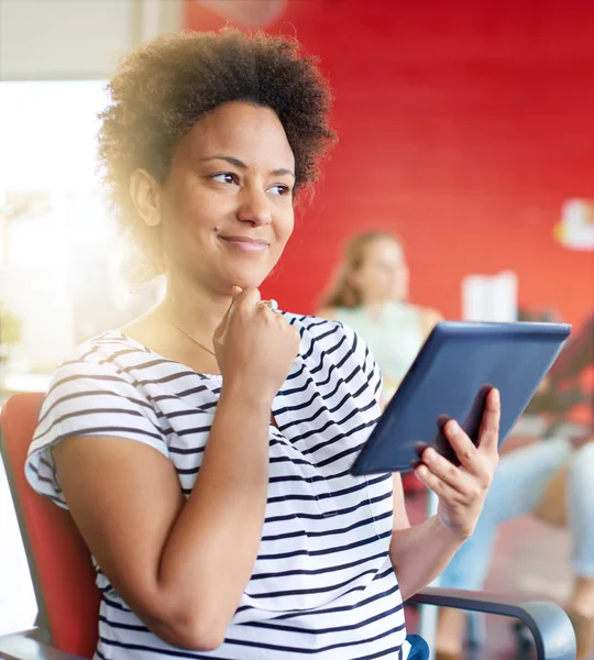 Diseñadora femenina segura trabajando en una tableta digital en un espacio de oficina rojo creativo —  Fotos de Stock