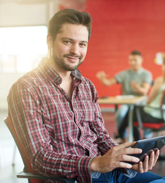 Diseñador masculino confiable trabajando en una tableta digital en el espacio de oficina creativo rojo — Foto de Stock