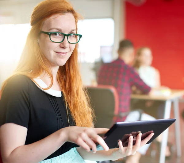 Conceptrice confiante travaillant sur une tablette numérique dans un espace de bureau créatif rouge — Photo