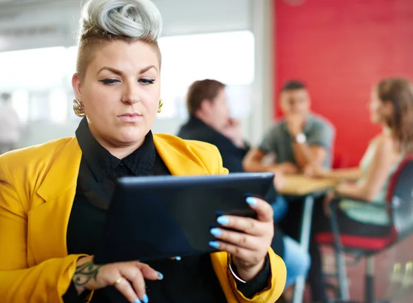Designer feminina confiante e nervosa trabalhando em um tablet digital no espaço de escritório criativo vermelho — Fotografia de Stock